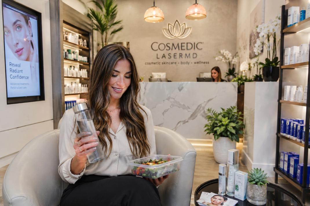 Professional woman balances wellness habits with skincare routine inside bright modern clinic.